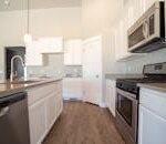 Spacious modern kitchen with white cabinets and stainless steel appliances.